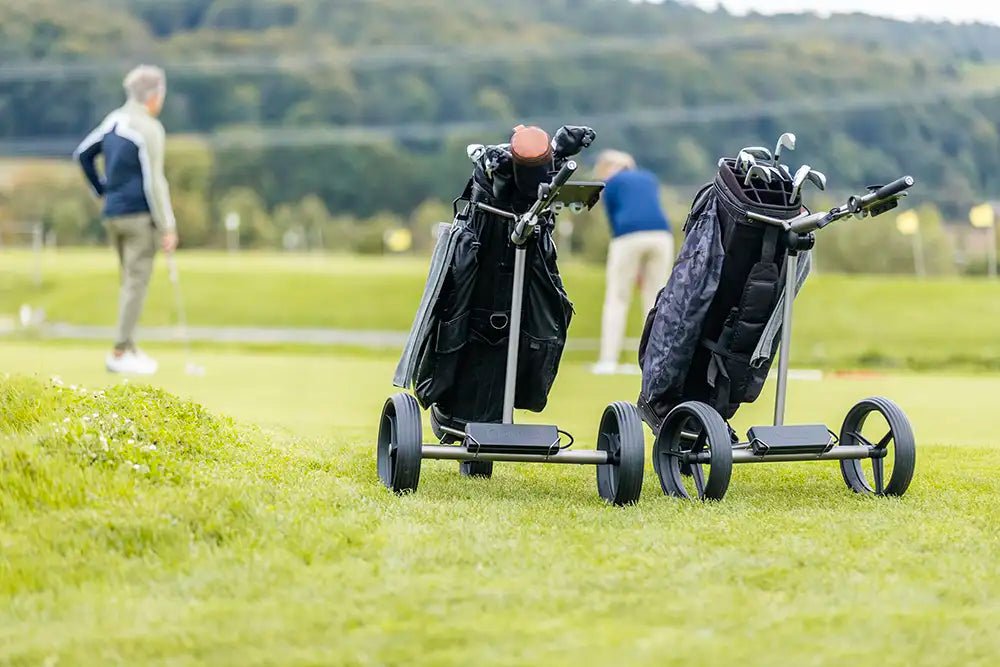 Zwei GolfQuant 1e Titan-Golftrolleys mit Golfbags auf dem Fairway